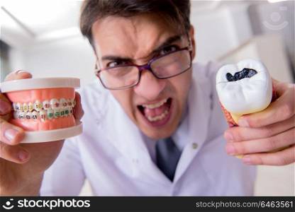 Funny dentist with teeth model in hospital