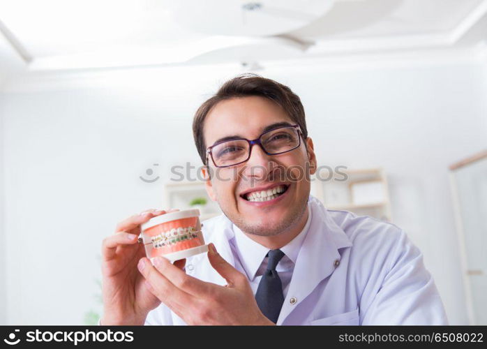 Funny dentist with teeth model in hospital