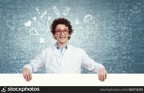 Funny doctor with billboard. Young male funny doctor showing white blank banner