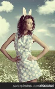 funny easter portrait of sensual brunette lady with curly hair, pink bunny ears and spring dress vintage color&#xA;