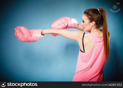 Funny girl female boxer model wearing big fun pink gloves playing sports boxing studio shot blue background