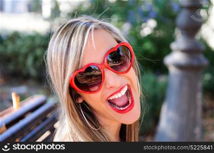 Funny girl with red heart glasses in a park