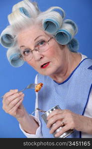 funny grandmother eating canned food with fork