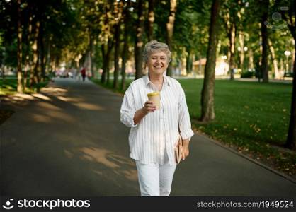 Funny granny drinks coffee in summer park. Aged people lifestyle. Pretty grandmother having fun outdoors, old female person outdoor. Funny granny drinks coffee in summer park
