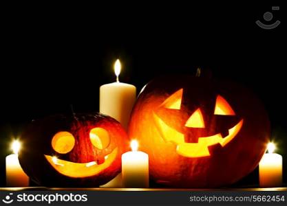 Funny Halloween pumpkin and burning candles on black background