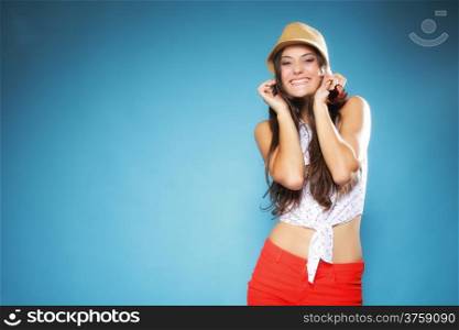 Funny happy girl woman long hair in summer clothes and hat having fun. Studio shot on blue. Youth and vacation concept.