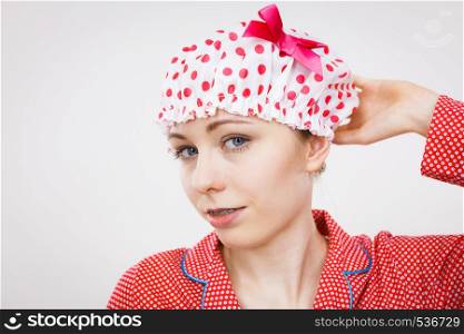 Funny happy woman after shower wearing pink pajamas and dotted bathing cap. Funny woman wearing pajamas and bathing cap