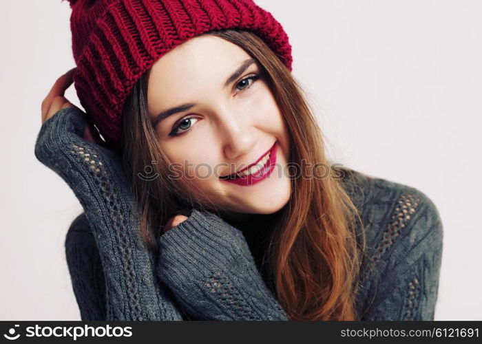 Funny hipster girl in knitted grey sweater and beanie marsala hat. Bright lips, having fun. Trendy casual fashion outfit in winter.