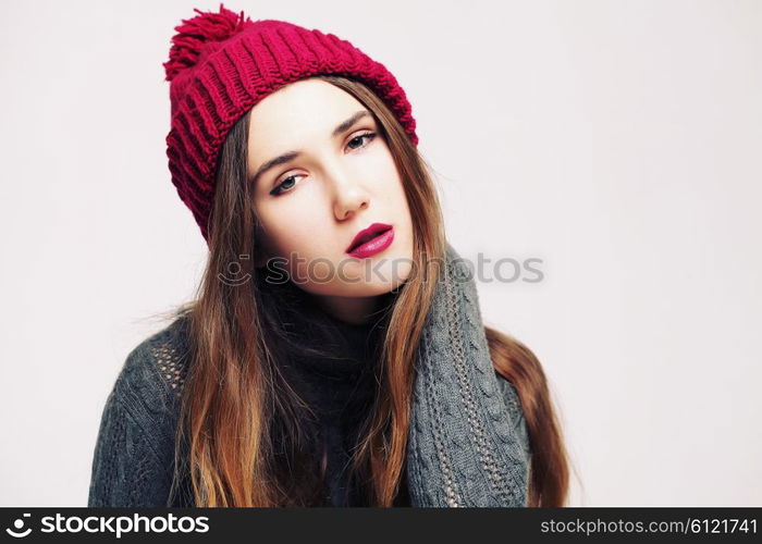 Funny hipster girl in knitted grey sweater and beanie marsala hat. Bright lips, having fun. Trendy casual fashion outfit in winter.