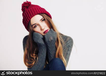 Funny hipster girl in knitted grey sweater and beanie marsala hat. Bright lips, having fun. Trendy casual fashion outfit in winter.