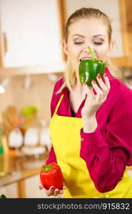 Funny joyful woman holding bell pepper delicious healthy dieting vegetable trying to take a bite in kitchen.. Funny woman taking bite of bell pepper