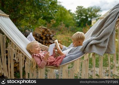 Funny kids lying in a hammock, summer camping. Family with children travel in camp car, nature and forest on background. Campsite adventure, travelling lifestyle. Funny kids lying in a hammock, summer camping