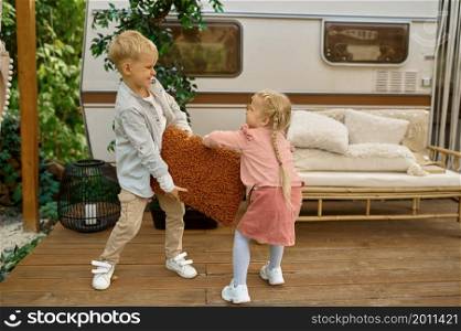 Funny kids play at the trailer, summer camping. Family with children travel in camp car, nature and forest on background. Campsite adventure, travelling lifestyle. Funny kids play at the trailer, summer camping