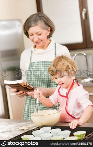 Funny little girl baking cupcake with grandmother hold whisk