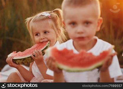 Funny little girl biting a slice of watermelon outdoors on warm and sunny summer day. happy childhood. selective focus.. Funny little girl biting a slice of watermelon outdoors on warm and sunny summer day. happy childhood. selective focus