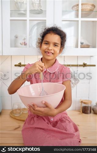 Funny little girl cooking the dough, nice breakfast. Smiling female child on kitchen in the morning. Happy childhood, young cook. Little girl cooking the dough, nice breakfast