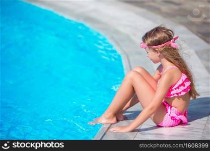 Funny little girl have a fun with a splash near swimming pool. Little girl having fun with a splash near swimming pool