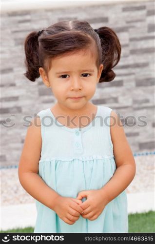 Funny little girl with blue dress looking at camera outdoor