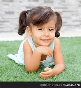 Funny little girl with pigtails lying on the grass