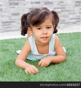 Funny little girl with pigtails lying on the grass