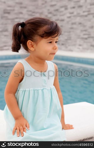 Funny little girl with pigtails sitting near the pool