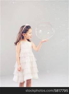 Funny lovely little woman playing with soap bubbles