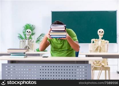 Funny male student in the classroom with skeleton 