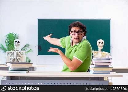 Funny male student in the classroom with skeleton 