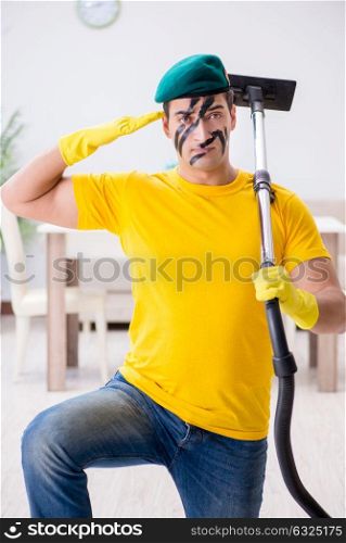 Funny man in military style cleaning the house