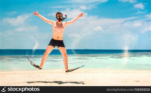 Funny man jumping in flippers and mask. Holiday vacation on a tropical beach at Maldives Islands.