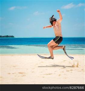 Funny man jumping in flippers and mask. Holiday vacation on a tropical beach at Maldives Islands.