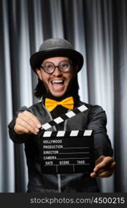 Funny man with movie board against curtain