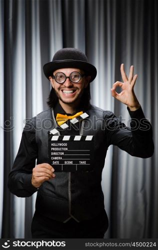 Funny man with movie board against curtain