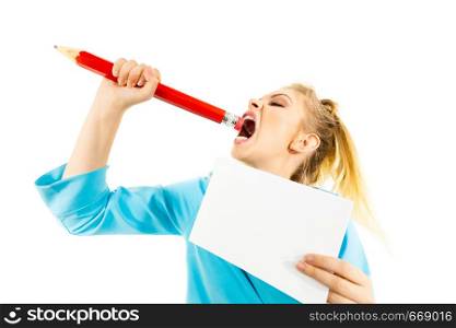 Funny nervous woman being stressed out about work or school. Teenage female holding piece of paper and biting big oversized pencil. Funny woman biting big pencil