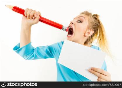 Funny nervous woman being stressed out about work or school. Teenage female holding piece of paper and biting big oversized pencil. Funny woman biting big pencil