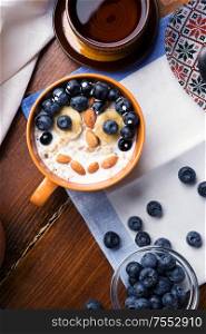 funny oatmeal porridge with blueberries, fruits, almonds and coconut milk. Healthy and tasty vegan breakfast. top view, flat lay.
