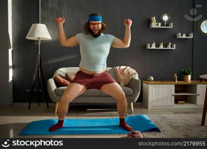 Funny oversize man showing strong muscles power. Sport training with dumbbells at home. Funny oversize man showing strong muscles power