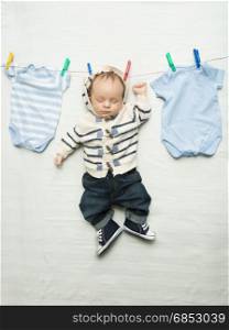 Funny photo of cute baby boy hanging on clothesline