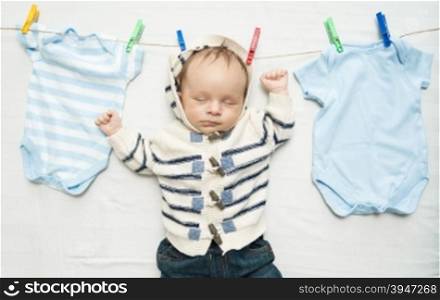 Funny photo of cute baby boy hanging on clothesline next to drying clothes