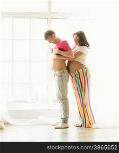 Funny photo of pregnant wife hugging husband with big abdomen