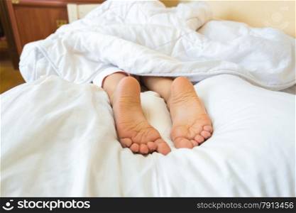 Funny photo on bed of girls feet lying on pillow