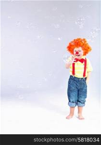 Funny picture of little clown making large soap bubbles