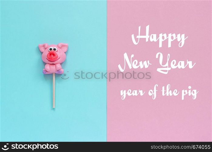 Funny pink pig lollipop and inscription Happy New Year, Year of the pig on pink blue background. Top view Concept greeting card Year of the pig.. pig lollipop and text Happy New Year