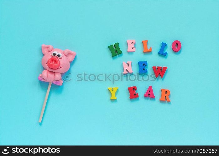 Funny pink pig lollipop and multicolor inscription Hello New Year on blue background. Top view Layout Concept greeting card Year of the pig.. pig lollipop and text Hello New Year