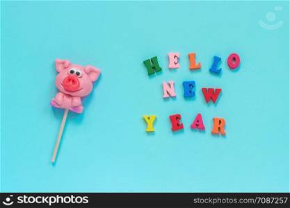 Funny pink pig lollipop and multicolor inscription Hello New Year on blue background. Top view Layout Concept greeting card Year of the pig.. pig lollipop and text Hello New Year