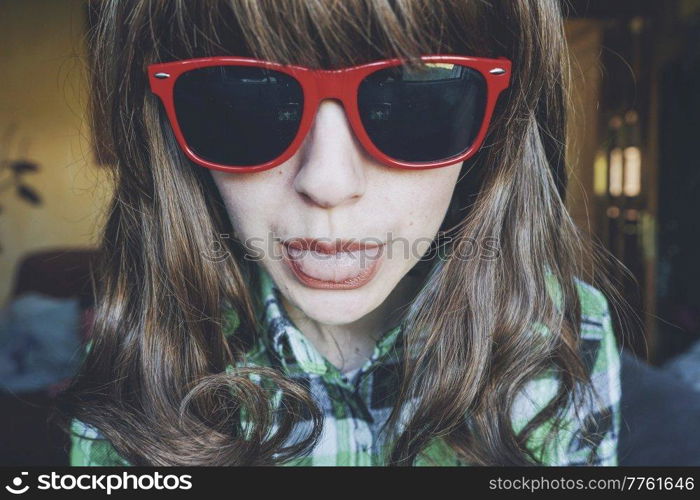 Funny portrait of a young woman wearing red sunglasses