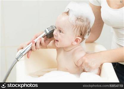 Funny portrait of baby playing in foam at bathroom