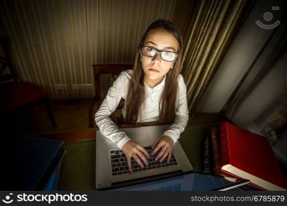 Funny portrait of computer geek girl sitting at laptop at night