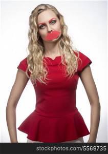 funny portrait of nice blonde female posing with fake mouth and eyebrows, long wavy hair, wearing red dress. Photo booth concept