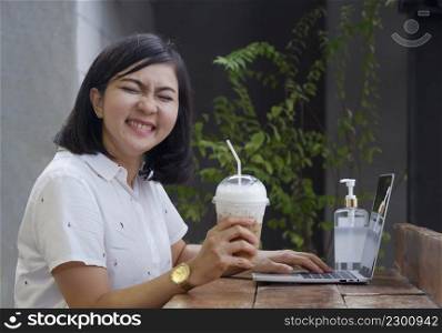 Funny portrait of young Asian woman smiling and laughing while relaxing on terrace at coffee shop